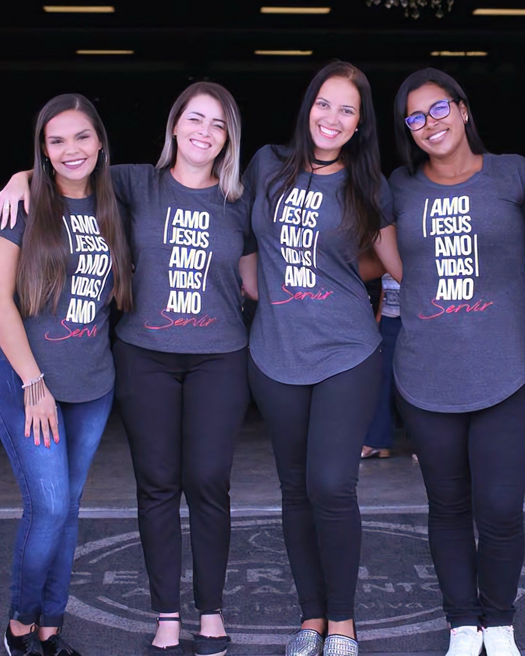 Mulheres com camisetas cinzas do evento Amo Jesus