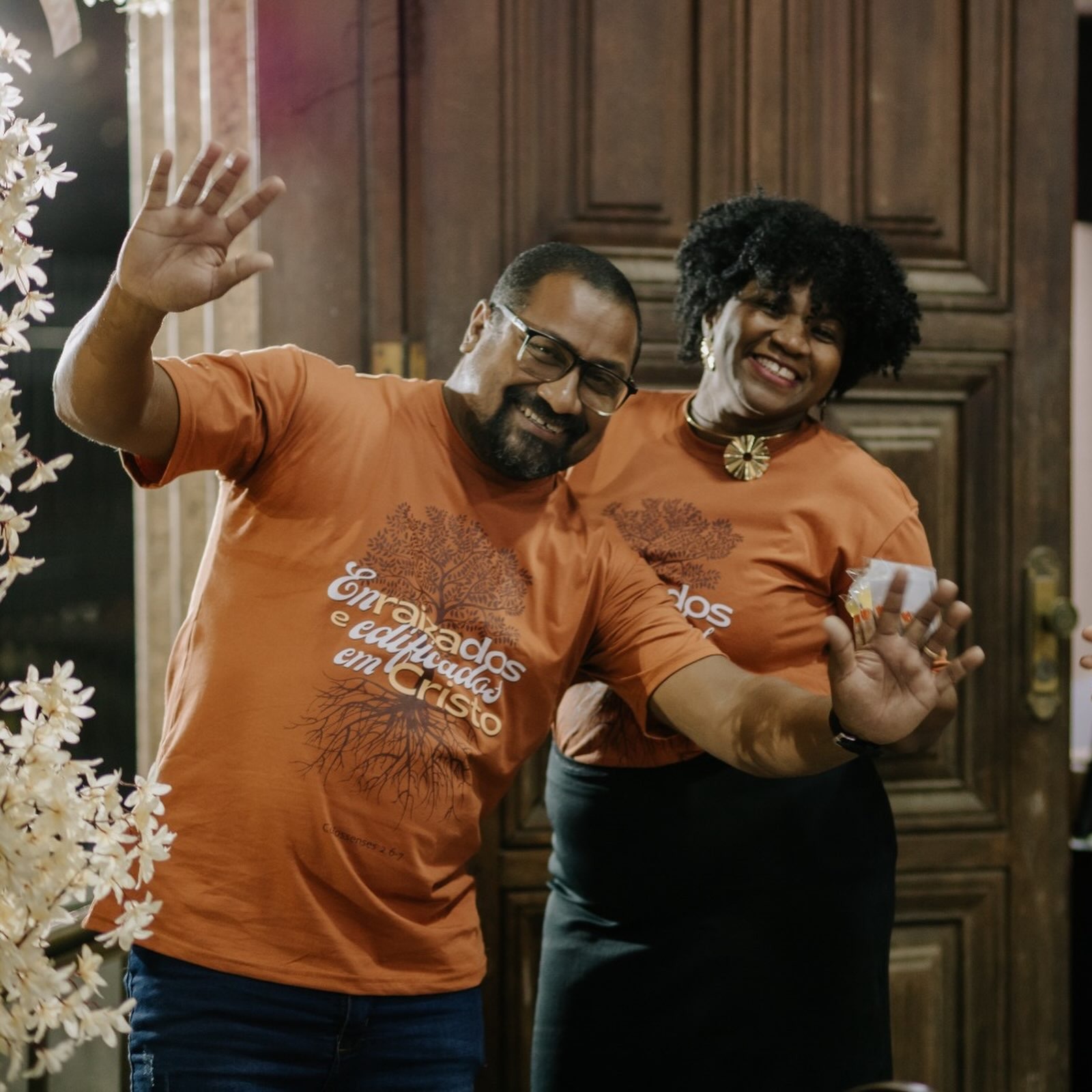 Casal com camisetas laranjas da festividade Enraizados e Edificados em Cristo